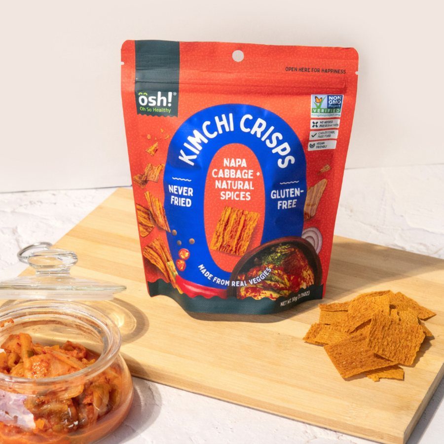 Kimchi Baked Crisps pack beside a jar of kimchi and crisps on a board