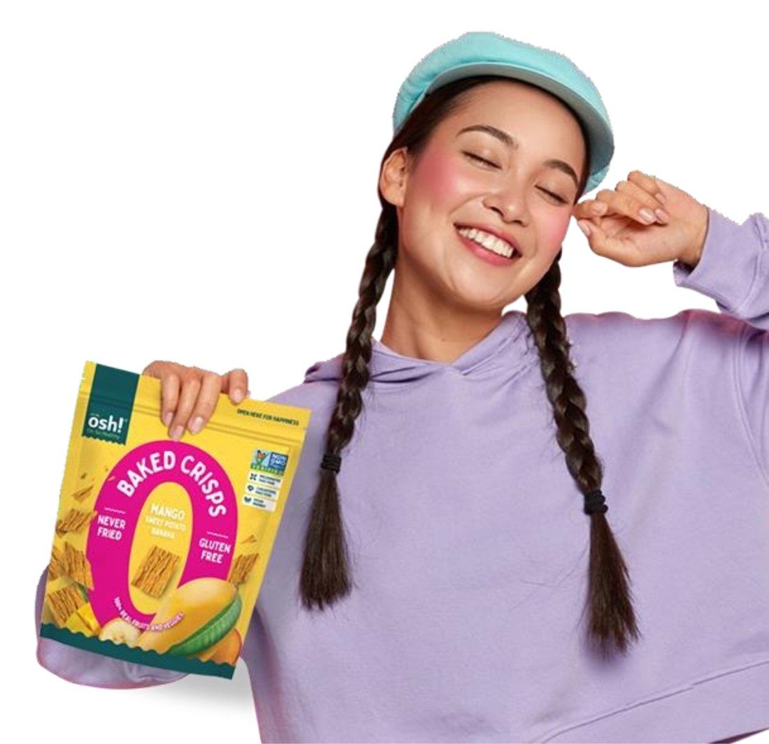 Smiling woman in a lilac hoodie and teal cap holding a Mango baked crisps pack