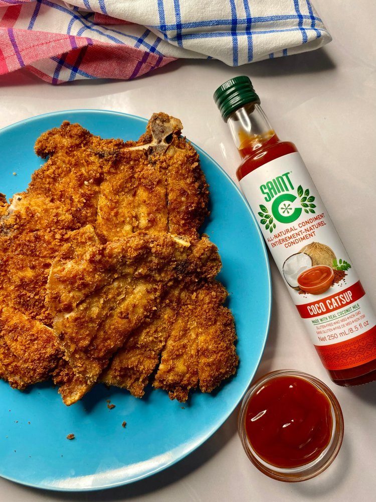 Saint C Coco Catsup bottle and a dip bowl beside crumbed pork chops
